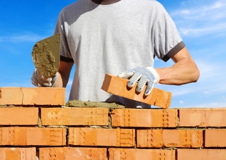 15314663 - bricklayer laying bricks to make a wall